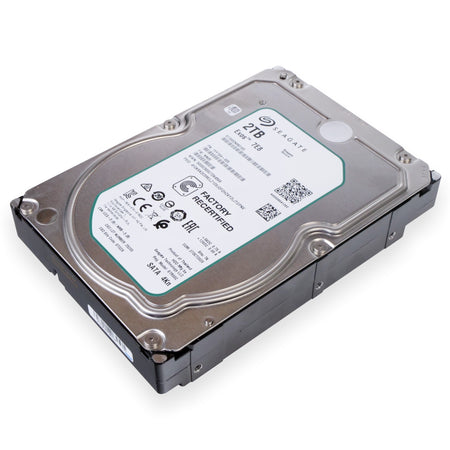 An angled perspective view of a 3.5-inch Seagate Exos 7E8 internal hard drive with a 2TB capacity. The drive features a silver metallic top cover with a large white label prominently stamped with 'FACTORY RECERTIFIED' in bold black letters. The label includes the Seagate logo, various barcodes, QR codes, and regulatory certifications like CE, EAC, and UL.